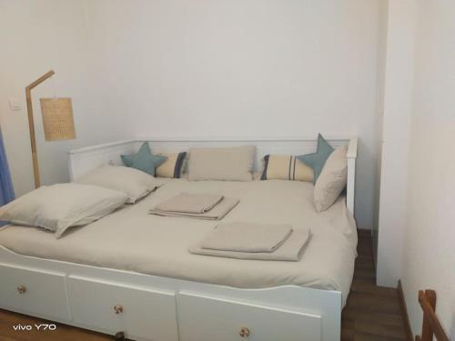 a white bed with blue pillows on it at Jolie maison paisible, avec jardinet et parking in Gujan-Mestras