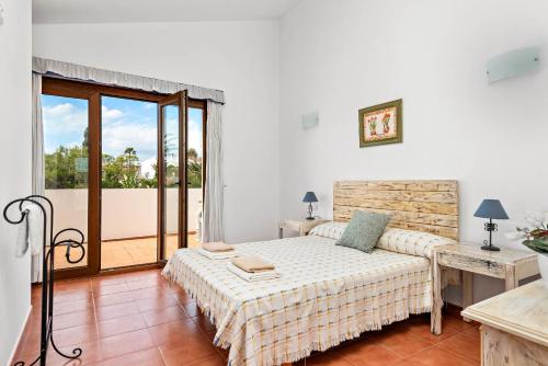 een witte slaapkamer met een bed en een balkon bij Villa Angel in Son Xoriguer