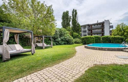 un patio trasero con piscina y cenador en Hotel Clariss en Balatonalmádi