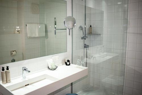 a white bathroom with a sink and a shower at Augarten Art Hotel, a Member of Design Hotels in Graz