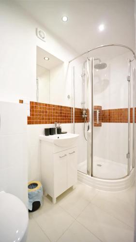 La salle de bains blanche est pourvue d'une douche et d'un lavabo. dans l'établissement Apartamenty EverySky - Karkonoska 30, à Karpacz