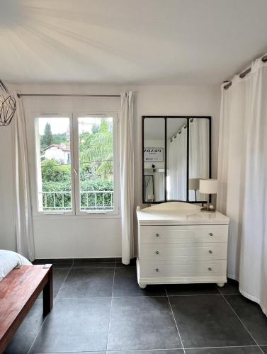 - une chambre blanche avec une commode et un miroir dans l'établissement Maison de charme idéalement située, à Cannes