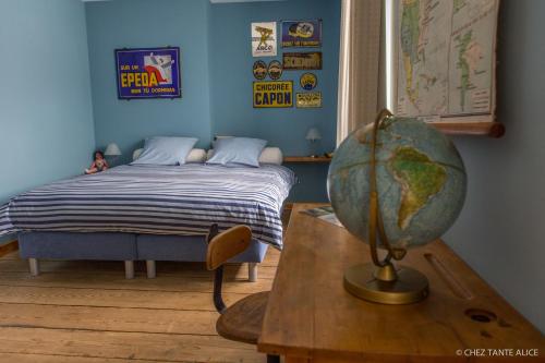 B&B Chez tante Alice في دربي: غرفة نوم مع سرير والكرة الأرضية على طاولة