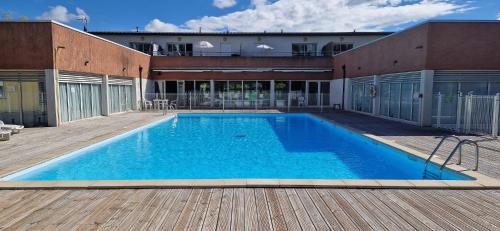 una grande piscina blu su una terrazza di legno di Vue sur le golf chez les grats-piscine-clim a Rivières