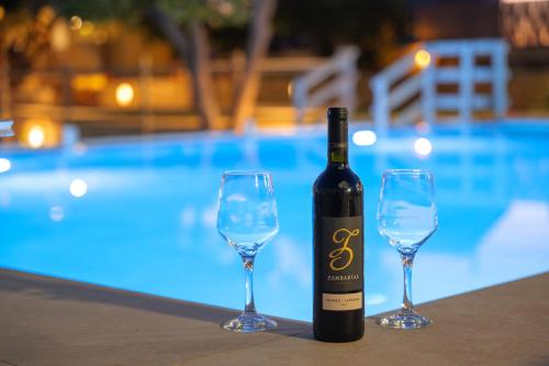 uma garrafa de vinho e dois copos de vinho ao lado de uma piscina em Villa Amarantos - Private pool em Stamnoí
