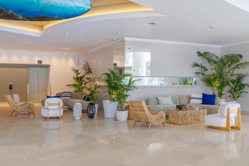 a lobby with chairs and couches and palm trees at Pestana Blue Alvor Beach - All Inclusive Hotel in Alvor