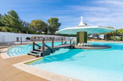 een zwembad met een tafel en een parasol bij Pestana Blue Alvor Beach - All Inclusive Hotel in Alvor