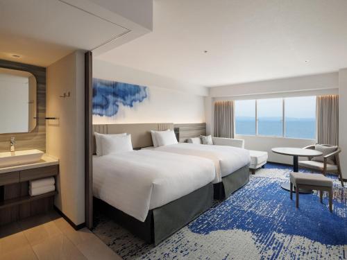 een hotelkamer met een groot bed en een badkamer bij Grand Mercure Beppu Bay Resort & Spa in Beppu