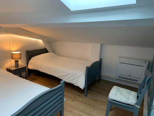 a attic room with two beds and a chair at Les Hortensias in Caumont-sur-Garonne