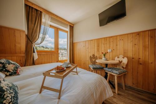 een slaapkamer met een bed en een tafel en een televisie bij GOŚCINA u MARYNY Sauna & Balia in Poronin