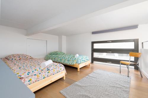 une chambre avec deux lits et une chaise et une fenêtre dans l'établissement le Loft du Stade - 6 chambres - terrasse - arcade, à Saint-Denis