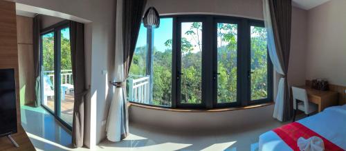 a bedroom with a large window with a view at Bangnu Greenery Resort in Takua Thung