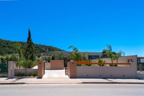 a house with a white fence and a street at Afesou Suites in Ialyssos