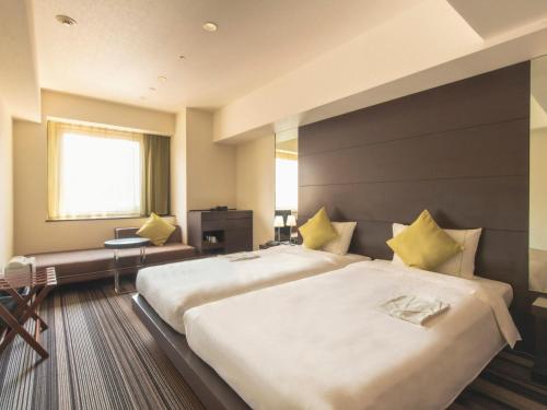 a hotel room with two beds and a desk at Hotel Brighton City Osaka Kitahama in Osaka