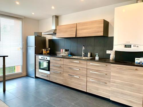 une cuisine avec des armoires en bois et un réfrigérateur dans l'établissement Apt Val d'Europe - 10 min de Disney - Parking, à Montévrain