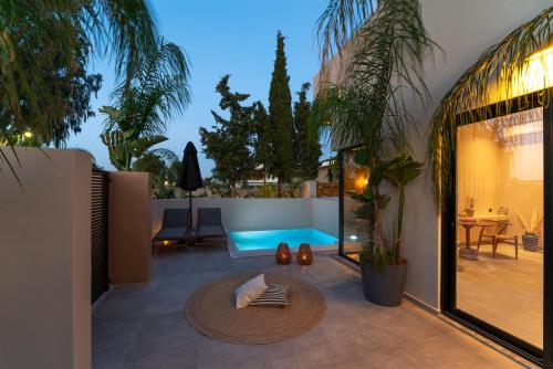 a patio with a table and a swimming pool at Afesou Suites in Ialyssos