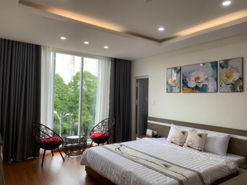 una camera da letto con un letto con due sedie e una finestra di Khách sạn Khang An Buôn Ma Thuột a Buôn Ma Thuột