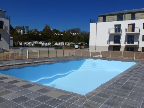 une grande piscine d'eau bleue devant un bâtiment dans l'établissement Au gré des Vagues, vue mer, wifi, piscine chauffée, à Concarneau