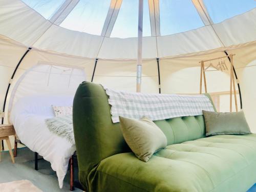 un sofá verde en una tienda con cama en Luxury Stargazing Glamping - Seren Aur with Hot Tub, en Llanidloes
