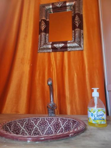 a bathroom sink with a mirror and a soap bottle at Bright Star Desert Camp in Merzouga