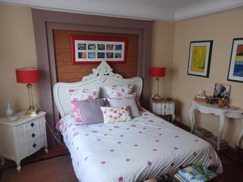 Un dormitorio con una cama blanca con almohadas rosas y moradas en Comme chez Vous, en Briis-sous-Forges