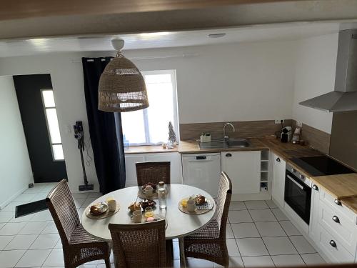 eine Küche mit einem weißen Tisch und Stühlen sowie eine Küche mit einem Tisch in der Unterkunft Gîte à Saint-Marcan-Baie du Mont-Saint-Michel in Saint-Marcan