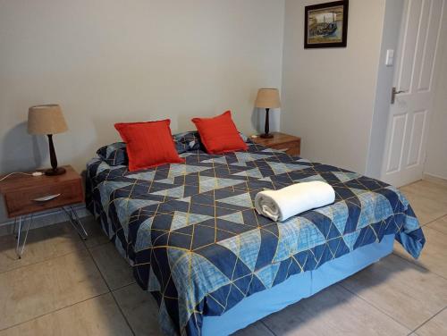 a bedroom with a bed with two red pillows at Olive's Nest 2 in Velddrif