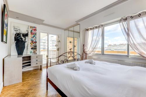 une chambre avec un lit blanc et une grande fenêtre dans l'établissement Appartement avec balcon Quartier branché, à Paris