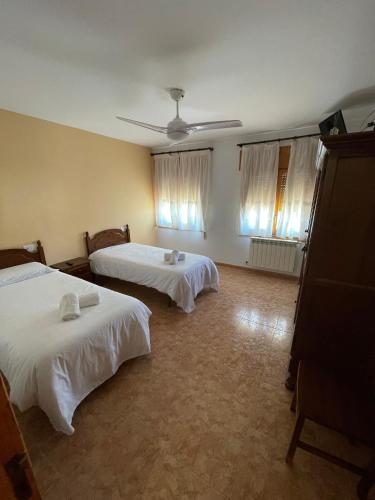 a bedroom with two beds and two windows at Hostal La Rurala Estopanyà in Estopiñán