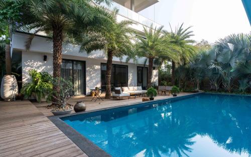 a swimming pool with palm trees and a house at Amorzito by Solitaire Stays in Marmagao