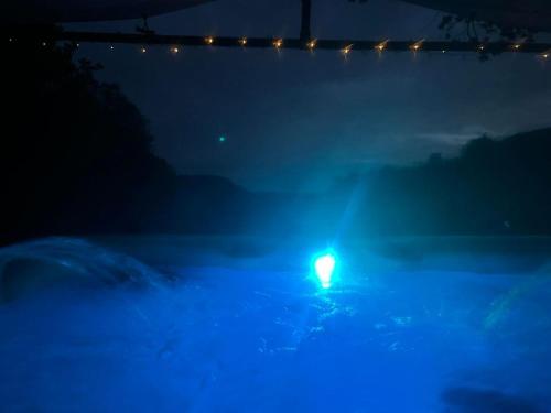 a blue light in a swimming pool at night at 'Morris' the shepherd's hut with woodland hot tub in Carmarthen