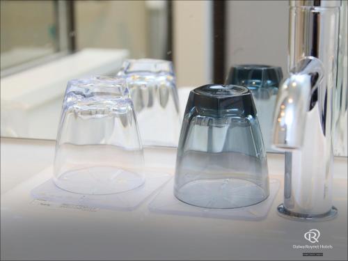 a row of glasses sitting on a bathroom sink at Daiwa Roynet Hotel Chiba Ekimae in Chiba
