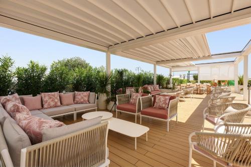 an outdoor patio with couches and tables and chairs at Hotel Aurora in Lido di Jesolo