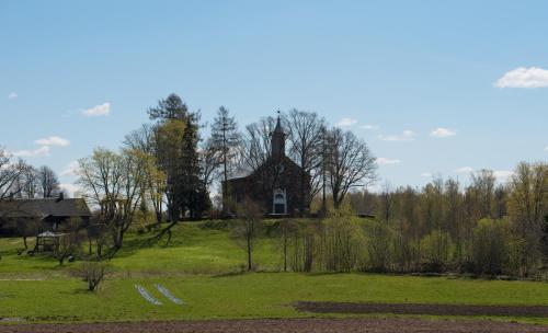 an old church on top of a grassy hill at Guest House BENHAUS ar pirti un āra kublu in Sarkaņi