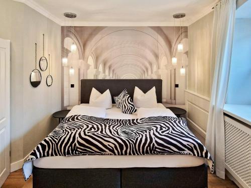 a bedroom with a large bed with zebra print sheets at Boutique Hotel POST ANDECHS in Andechs