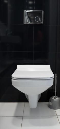 a white toilet in a bathroom with a black wall at Aparthotel Strefa Budget in Tychy