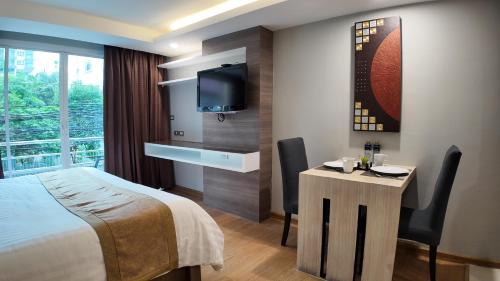 バンコクにあるAspira Suites Sukhumvit 20のベッド、テーブル、テレビが備わる客室です。
