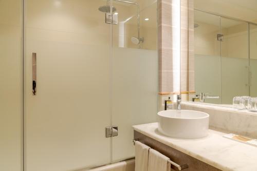 a bathroom with a sink and a glass shower at Pestana Blue Alvor Beach - All Inclusive Hotel in Alvor