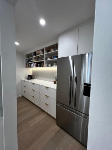 a kitchen with white cabinets and a stainless steel refrigerator at Retreat on Fig Street in Dromana