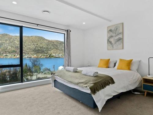 Un dormitorio con una cama y una ventana grande. en Contemporary & Plush - 3 Bedroom House Near Marina, en Queenstown