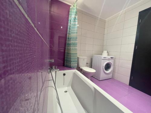 a purple bathroom with a toilet and a washing machine at Majestic Sunset in Mastichari