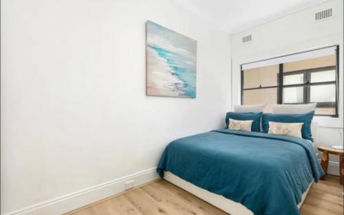 a bedroom with a bed with a blue blanket at Bondi Bliss ~ Stylish & Comfy Gem ~ Walk to Beach! in Sydney
