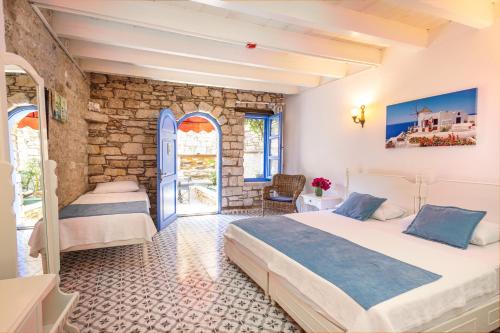 1 dormitorio con 2 camas y pared de piedra en Alacati Eski Ev Hotel en Alacati