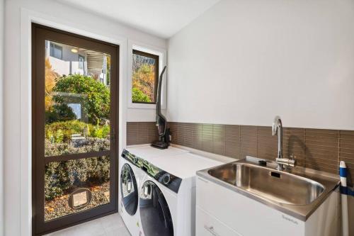 a kitchen with a sink and a washing machine at Luxury Retreat - Matakauri in Queenstown