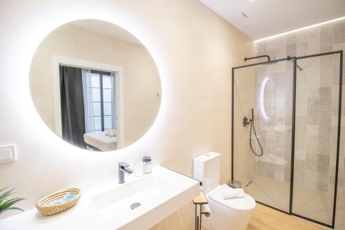 een witte badkamer met een wastafel en een spiegel bij BedTime Suites by Concept Flats in Valencia