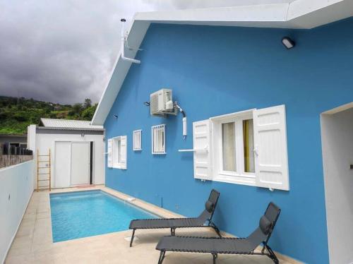 Una pared azul con dos sillas y una piscina. en Villa Cannelle 2, en Étang-Salé