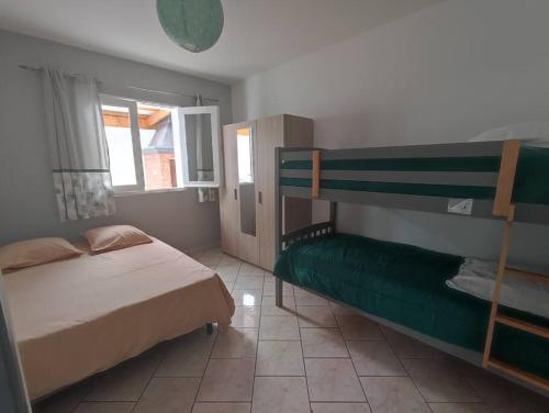 Un dormitorio con dos literas y una ventana. en Villa Cannelle 2, en Étang-Salé