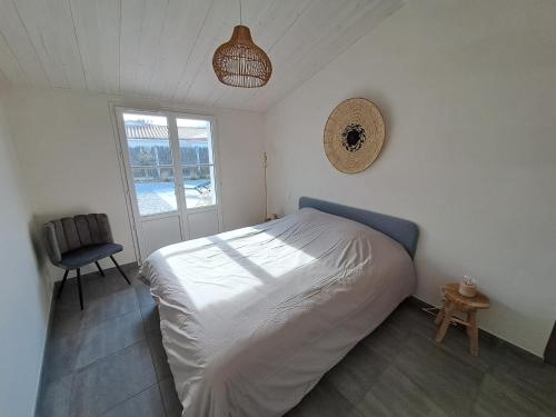 a bedroom with a bed and a chair and a window at L'Épine - Maison lumineuse - 300m de la plage in LʼÉpine