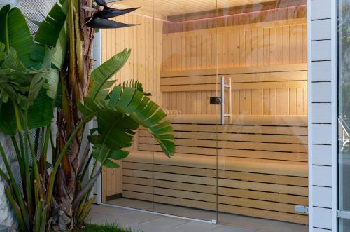 a sauna with a glass door next to a plant at 1935 Hotel Boutique by Terraza in Roses