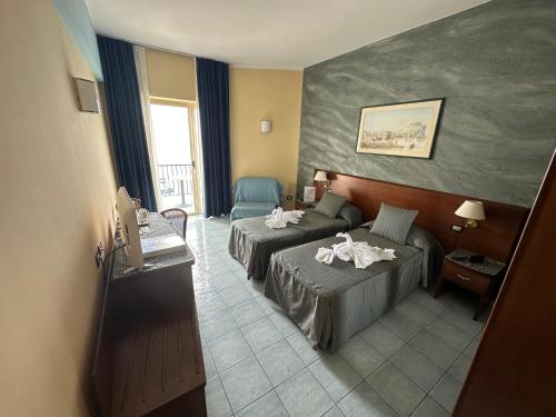 Habitación de hotel con 2 camas y sofá en Grand Hotel L'Approdo en Terracina